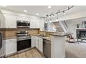 Well-lit kitchen with stainless steel appliances, granite countertops, and modern track lighting adjacent to living room at 836 S Vance St # E, Lakewood, CO 80226