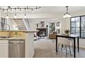 Open living space with fireplace, staircase, and adjacent kitchen, illuminated by modern track lighting and natural light at 836 S Vance St # E, Lakewood, CO 80226