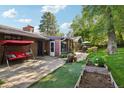 Inviting backyard features a brick patio with swing, garden beds, and mature trees offering a serene outdoor space at 13140 W 15Th Dr, Golden, CO 80401
