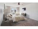Cozy bedroom with plush carpet, large window, mounted TV, and neutral tones creating a relaxing space at 13618 E Bethany Pl # 306, Aurora, CO 80014