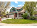 Inviting two-story home with brick accents, a spacious lawn, and mature trees at 1535 Peach Ct, Brighton, CO 80601