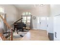 Grand foyer featuring hardwood floors, a black piano, and a front door with glass details at 1535 Peach Ct, Brighton, CO 80601