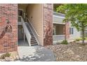 Condo exterior featuring brick accents, stairs leading to upper units, and rock landscaping, adding character and charm to the building at 8481 W Union Ave # 2-103, Littleton, CO 80123