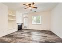Bright living room with fireplace, built-in shelving, ceiling fan, and wood-look flooring, creating a cozy and modern space at 8481 W Union Ave # 2-103, Littleton, CO 80123