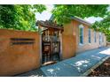 Unique Santa Fe-style home exterior with a rustic wooden gate, adobe walls and mature trees at 807 9Th St, Golden, CO 80401
