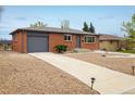 Inviting brick home with gravel landscaping and a paved driveway leading to a gray garage door at 740 Lotus Way, Broomfield, CO 80020