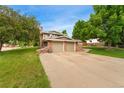 Charming two-story home with a brick facade, attached two-car garage, and a lush green lawn at 6798 Depew St, Arvada, CO 80003