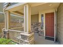 Inviting front porch showcasing stone columns, wood railing, and a stylish front door at 7838 W Layton Way, Littleton, CO 80123