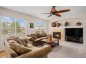 Comfortable living room with a fireplace, large windows, and a ceiling fan at 15901 E 106Th Way, Commerce City, CO 80022