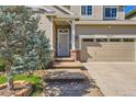 Inviting front entrance with stone steps, beige siding, and a well-manicured yard with a beautiful blue spruce tree at 10201 Rifle St, Commerce City, CO 80022