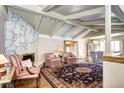 Bright living room boasts stone fireplace, beamed ceilings, and hardwood floors at 3820 S Ames St, Denver, CO 80235