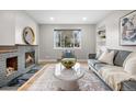 Bright living room featuring a stone fireplace, hardwood floors, modern furniture, and a large window at 1295 Elm St, Denver, CO 80220