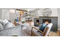 A well-decorated living room with a stone fireplace, hardwood floors, and updated kitchen in the background at 1295 Elm St, Denver, CO 80220