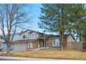Two-story home featuring brick accents, a spacious front yard, and mature trees under a clear blue sky at 3930 S Argonne Way, Aurora, CO 80013