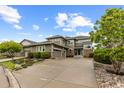 Well-maintained home with mature landscaping, long driveway, and attached garage in a suburban setting under a cloudy sky at 5319 W Hoover Dr, Littleton, CO 80123