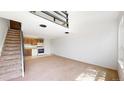 Bright living room with stairs, neutral carpet, white walls, and an adjacent kitchen space at 381 S Estes St # 1, Lakewood, CO 80226