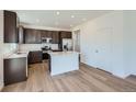 Contemporary kitchen featuring stainless steel appliances, dark cabinetry, center island and bright hardwood floors at 174 Baler Ct, Brighton, CO 80601