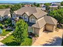 Aerial view showcases a well-maintained home with manicured landscaping, mature trees, and a paved driveway at 3400 Elk Run Dr, Castle Rock, CO 80109