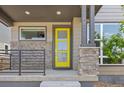 Welcoming front porch with stone accents, a yellow door, and modern railings enhance this home's curb appeal at 21482 E 60Th Ave, Aurora, CO 80019