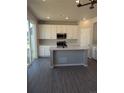 Modern kitchen featuring white cabinets, a large island, and gray flooring at 16830 Mckay Dr, Mead, CO 80542