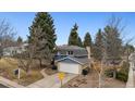 This two-story home features a charming brick and blue exterior, a two-car garage, and mature trees in the yard at 8785 E Floyd Cir, Denver, CO 80231