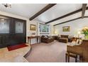 Inviting living room featuring exposed beams, comfortable furniture, and a decorative front door at 8785 E Floyd Cir, Denver, CO 80231