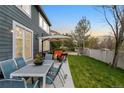 Beautifully landscaped backyard with a dining table, patio, seating area with a fire pit, and a privacy fence at 5910 W Sumac Ave, Littleton, CO 80123