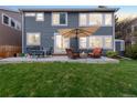 Spacious backyard with a concrete patio, dining table, chairs, and a cozy seating area with a fire pit at 5910 W Sumac Ave, Littleton, CO 80123