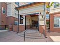 Close up exterior of building entrance with brick facade, stairs, and covered entry for Buildings A and B at 5677 S Park Pl # A102, Englewood, CO 80111