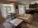 Bright and airy living room with a view of mature trees, adjacent to modern kitchen and dining area at 5677 S Park Pl # A102, Englewood, CO 80111