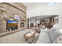 Inviting living room featuring a stone fireplace, neutral carpet, and a view into the kitchen at 2373 S Joyce St, Denver, CO 80228