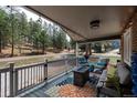 Cozy covered porch with seating, a fire pit, and scenic views of the surrounding woods at 5382 S Pine Rd, Evergreen, CO 80439