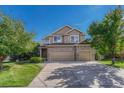 Charming two-story home with a three-car garage, brick accents, manicured lawn, and mature trees at 598 Crossing Cir, Castle Pines, CO 80108