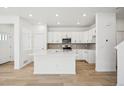 Bright, open kitchen featuring white cabinetry, stainless appliances, and a center island at 3325 N Coolidge Way, Aurora, CO 80019