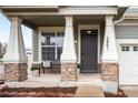 Inviting front porch with stone accents, a bench, and a stylish front door at 5861 Mt Shadows Blvd, Firestone, CO 80504