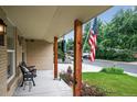 Inviting front porch with decorative columns, seating, and a view of the lush front yard at 11835 W 37Th Pl, Wheat Ridge, CO 80033
