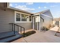 Side entrance featuring stairs, gray siding, and an exterior door, complemented by green bushes at 7176 S Vine E Cir, Centennial, CO 80122