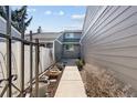 The image showcases a cement walkway leading to the front of the house, framed by fencing and landscaping at 7176 S Vine E Cir, Centennial, CO 80122