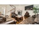 Cozy living room features hardwood flooring, a stone fireplace, and an adjacent staircase at 13341 Olive St, Thornton, CO 80602