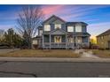 Charming two-story home with a welcoming front porch and well-maintained lawn at dusk at 3063 E 148Th Pl, Thornton, CO 80602
