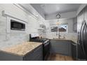 Gray cabinets and countertops highlight this home kitchen with tile backsplash, a microwave, and stainless steel appliances at 16120 E Radcliff Pl, Aurora, CO 80015