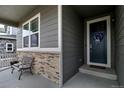 Inviting front porch with gray siding, stone accents, and a dark blue front door with decorative wreath at 26554 E Indore Ave, Aurora, CO 80016
