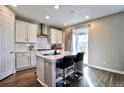 Bright kitchen featuring white cabinets, stainless steel hood, island seating, and sliding glass door at 26554 E Indore Ave, Aurora, CO 80016