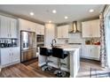 Modern kitchen with white cabinets, stainless steel appliances, a kitchen island, and hardwood flooring at 26554 E Indore Ave, Aurora, CO 80016