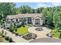 Beautiful home with circular driveway, fountain, manicured lawn, mature trees, and an impressive entrance framed with black trim at 4736 S Fillmore Ct, Cherry Hills Village, CO 80113