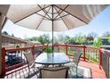 Inviting outdoor deck with a glass table, umbrella, and red railing, perfect for relaxing or entertaining at 9700 W 88Th Pl, Westminster, CO 80021