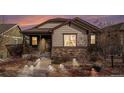 Beautiful single-story home with a covered porch, stone accents and walkway lighting at 4318 Fossil Way, Castle Rock, CO 80109