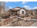 Charming home featuring a covered porch, rock landscaping with decorative metal wheel, and stone accents at 4318 Fossil Way, Castle Rock, CO 80109