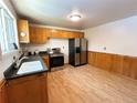 Well-lit kitchen featuring stainless steel appliances, wood laminate flooring, and wood paneled wall at 660 Wolff St, Denver, CO 80204