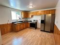 A clean kitchen with wood cabinets, a stainless steel refrigerator, and wood laminate flooring at 660 Wolff St, Denver, CO 80204